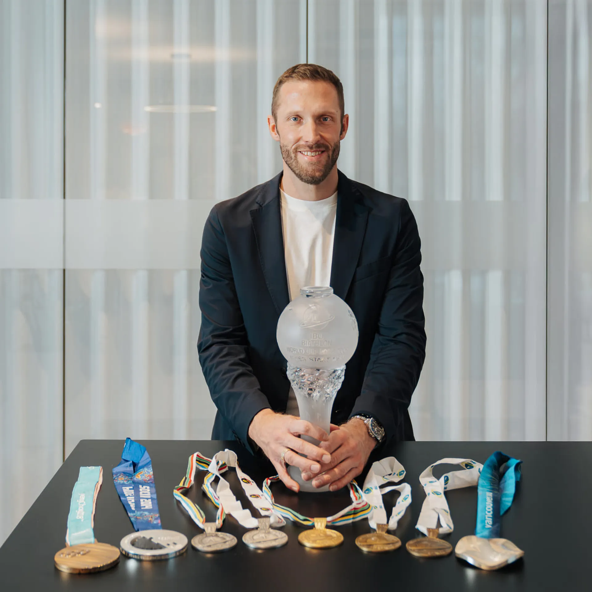 Dominik Landertinger mit Medaillen und Pokal am Tisch
