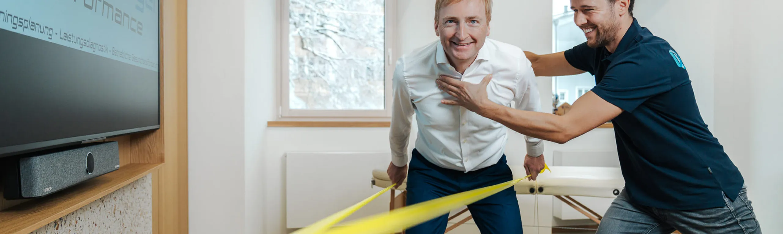Zwei Personen interagieren mit einem Widerstandsband in einem Raum.