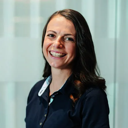 Lächelnde Person in sportlichem Oberteil, helle Umgebung